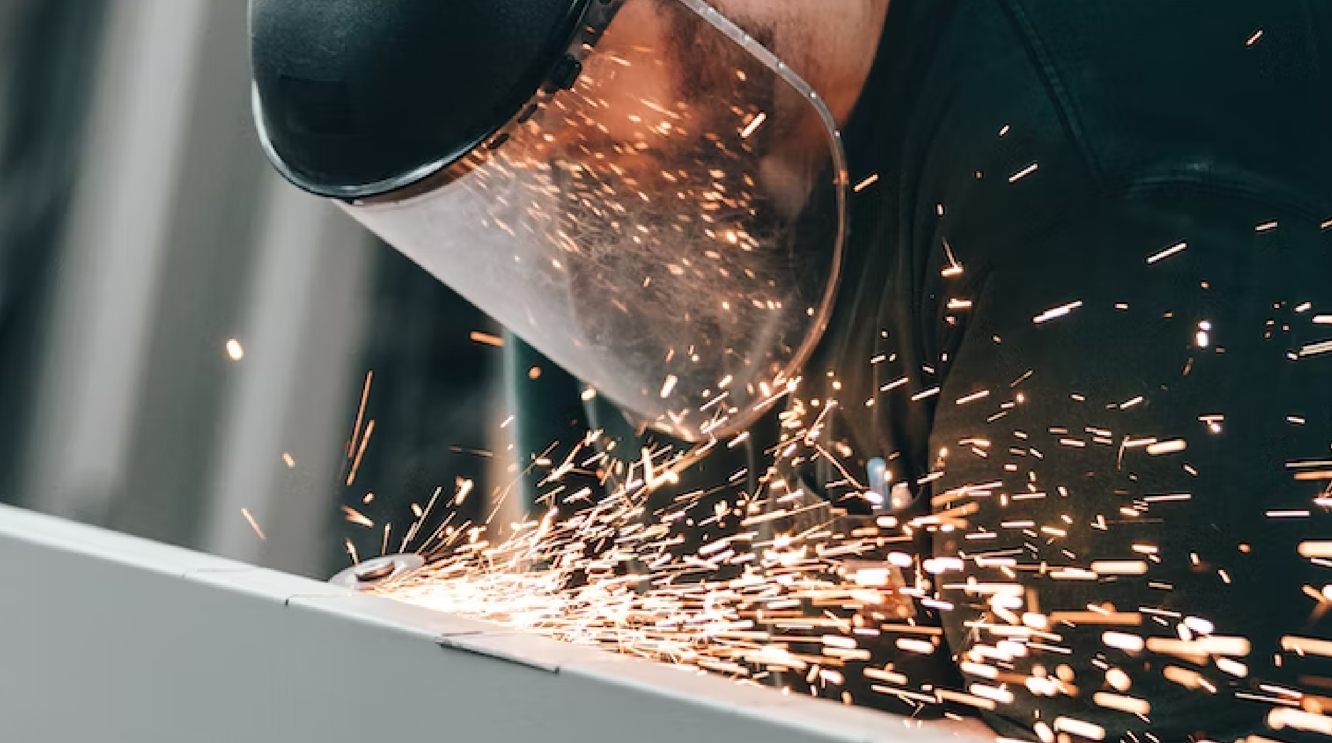 Professional welder in protective gear creates sparks welding at Pro-Type Industries.